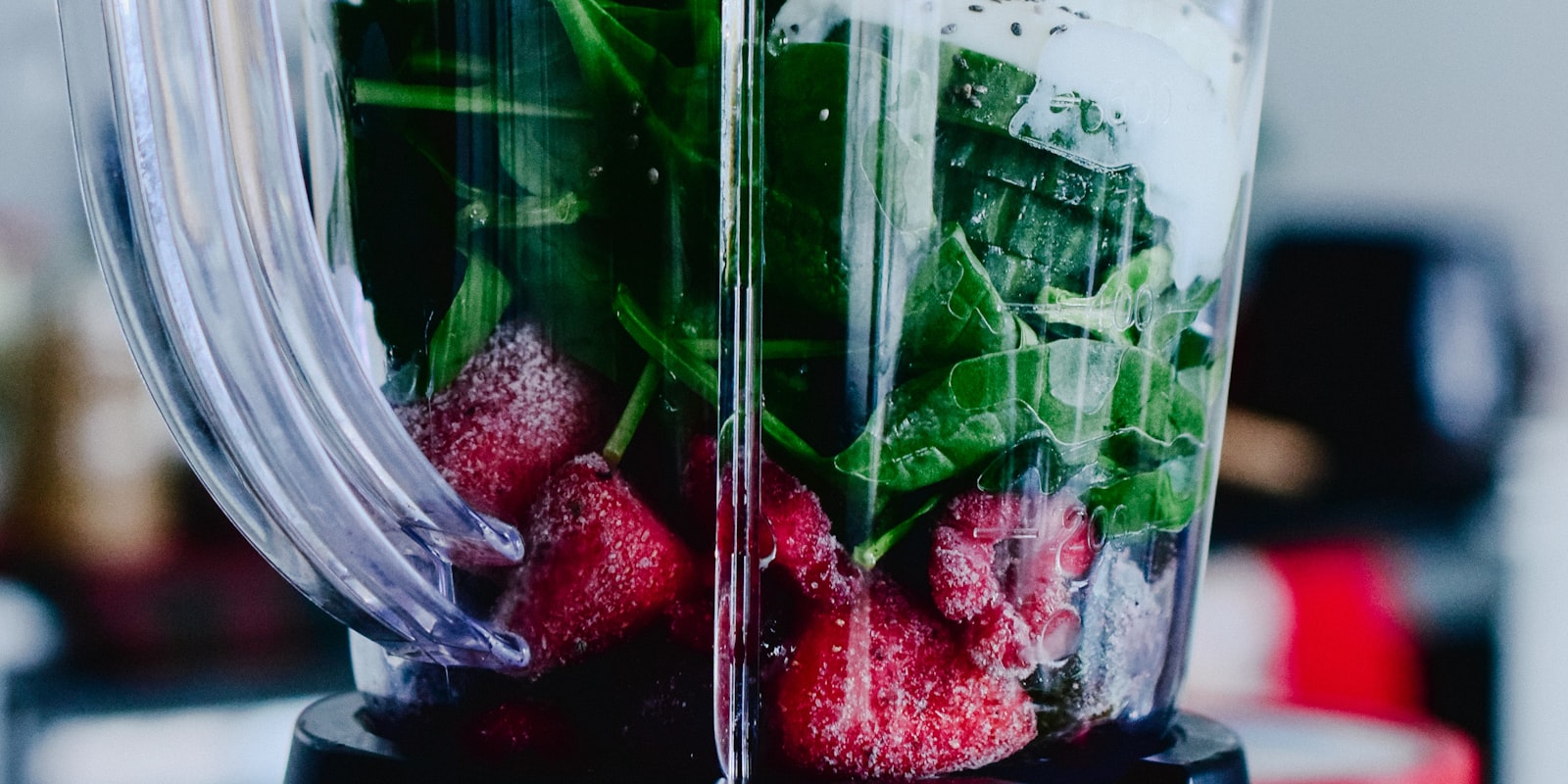 Blenderkan met spinazie en bevroren aardbeien op de motorvoet